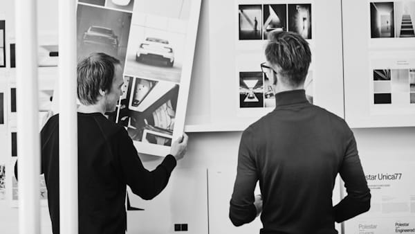 Two people, seen from behind, looking at photos on a wall