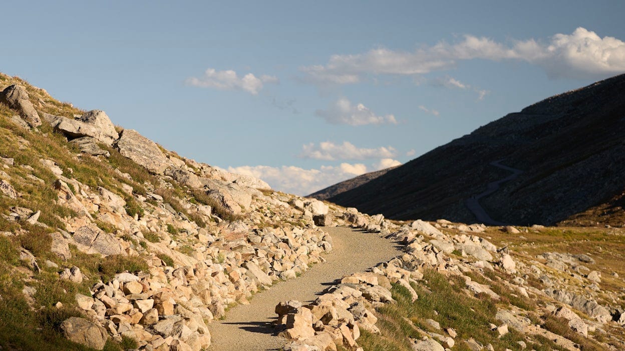 A mountain path with rocky terrain and a majestic mountain in the background.