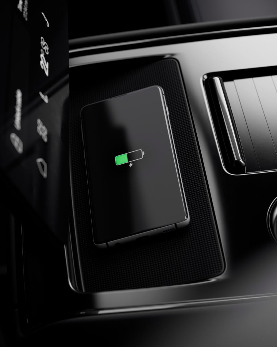 A mobile phone charges wirelessly using the car's interior charging.