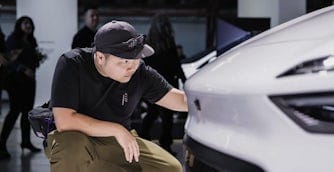 Man inspecting a white Polestar at a car event.